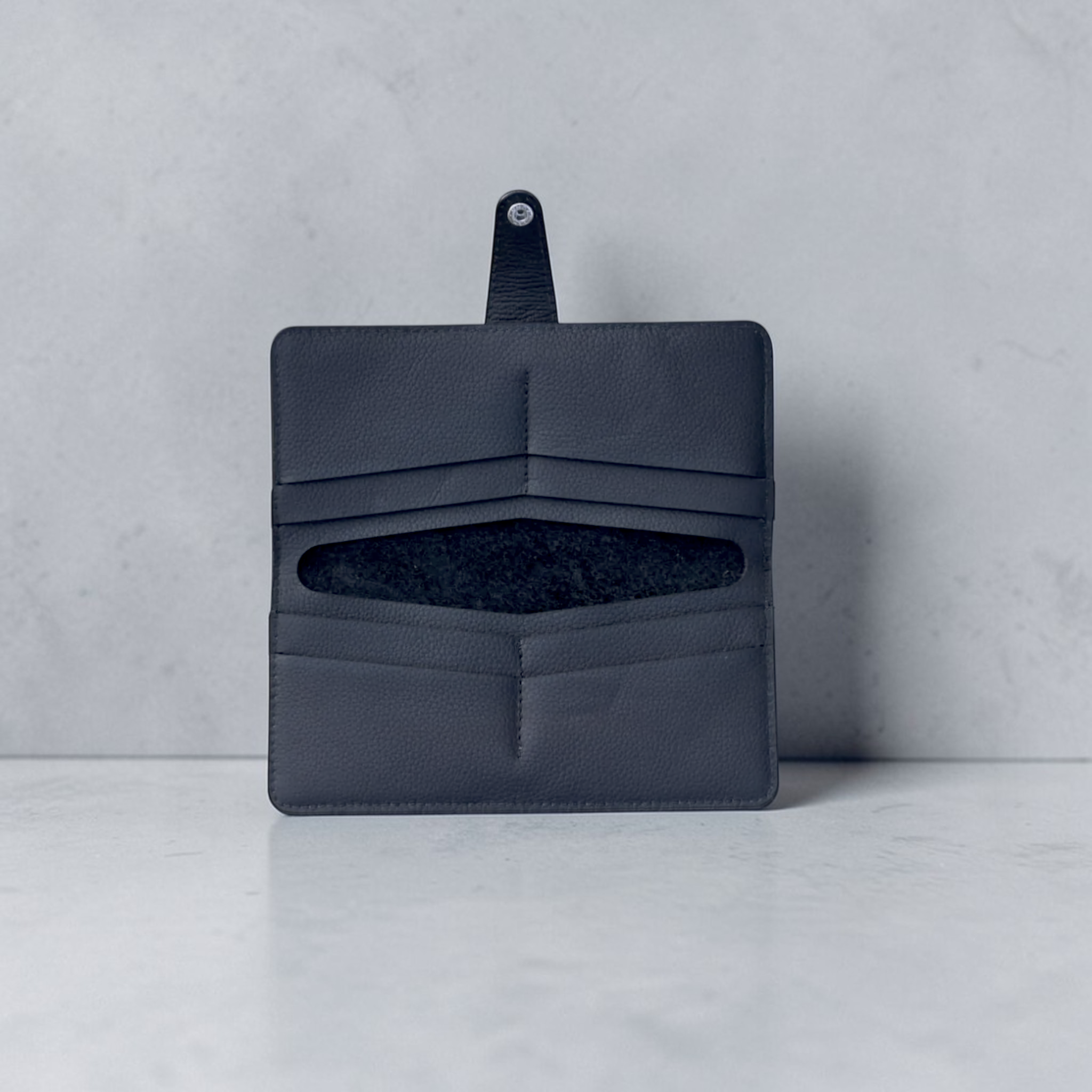 Minimalista Bag dark grey leather wallet with eight card slots and a central bill compartment, secured by a metal snap closure.